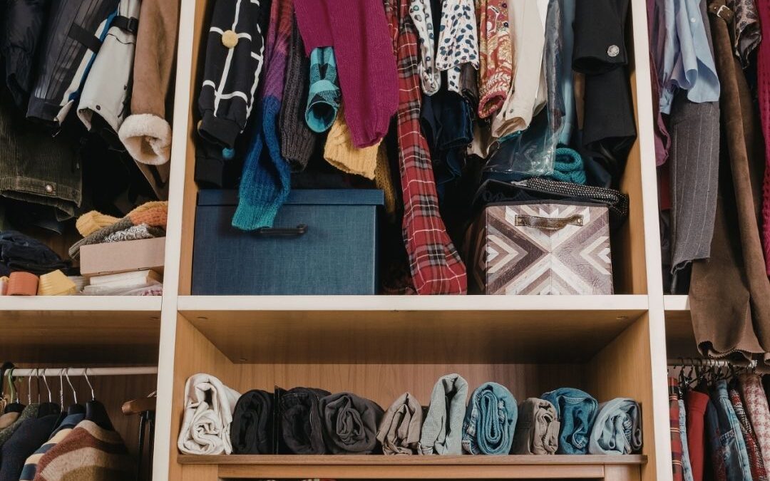 Organised wardrobe with clothes and memory box while sorting a deceased loved one’s clothing after bereavement.